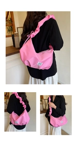 Detail of pink crossbody bag with pleated strap and fashion label on nylon fabric
