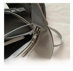 Close-up of silver leather bag featuring a smooth metal zipper and white lace flower detail