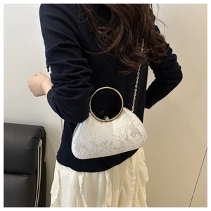 Rear view of a model styling white lace evening bag with gold ring handle and chain strap