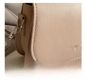 Macro detail of beige saddle bag showing precision stitching and metal hardware quality