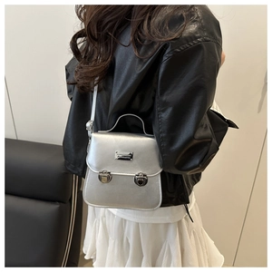 Detail of silver metallic bucket bag showing round clasps and decorative metal plate