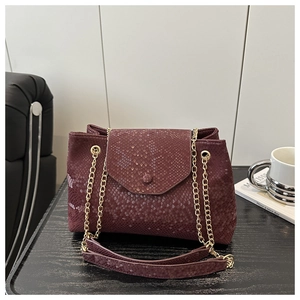 Détail du sac à bandoulière bordeaux motif serpent avec chaîne en métal doré