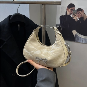 Sac hobo beige en forme de croissant avec texture plissée et nœud argenté