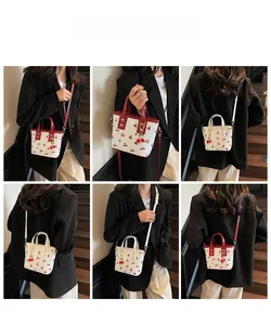 Detail of cherry print bucket bags showing crossbody and handheld styles on a model