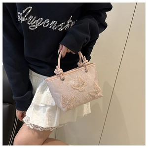 Detail of pink embroidered butterfly pattern and knotted handle on a Chinese style bucket bag