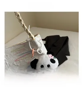 Close-up of cute panda plush charm with pink flower on textured tote bag details