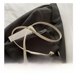 Detail of woven straw bucket bag with adjustable cream leather strap and gold buckle
