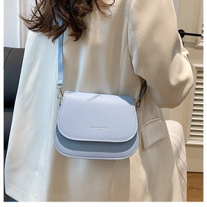 Detail of light blue PU leather saddle bag with adjustable strap on beige blazer outfit