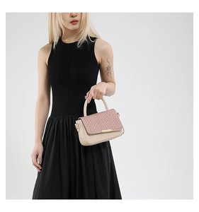 Détail du sac en similicuir beige avec rabat tissé à chevrons rouges et blancs et poignée
