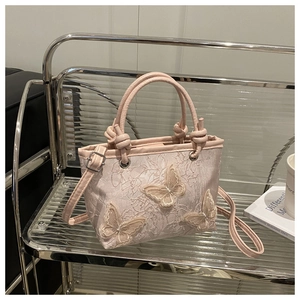 Dettaglio della borsa a secchiello in pizzo rosa con ricami di farfalle tridimensionali