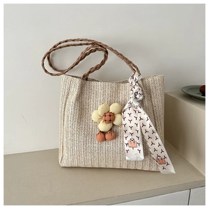 Detail of woven straw tote bag with brown leather handles and yellow floral charm
