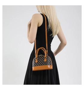 Detail of vintage shell-shaped crossbody bag with monogram pattern on fashion model