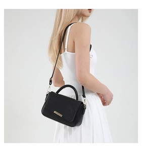 Détail du sac bandoulière noir avec rabat texture serpent et boucle métallique dorée chic