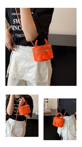Detailansicht der orangefarbenen gesteppten Mini-Umhängetasche mit Kettenriemen