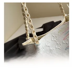 Detail of white textured tote bag with diamond embossing and woven braided handle strap