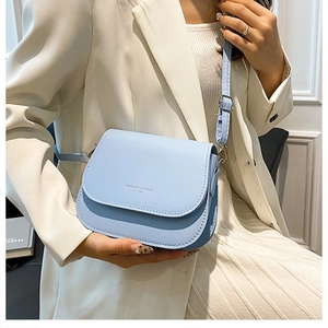Close-up of light blue flap crossbody bag with Fashion Trend text on white suit