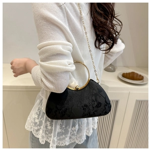 Detail of black jacquard evening bag with golden circular metal handle and chain strap