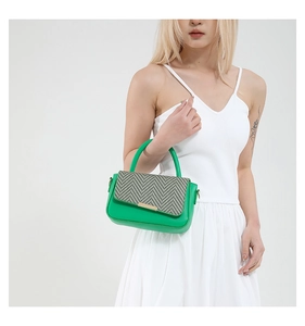 Detail of green leather handbag with black and white woven flap and gold metal trim