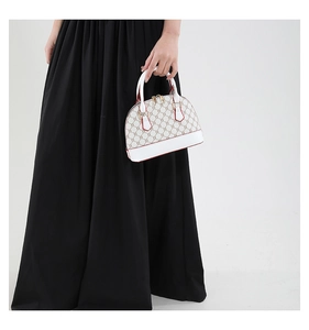 Close-up of white leather shell bag featuring vintage monogram pattern and golden zippers