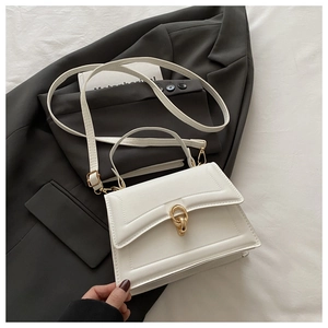 Detail of white rectangle crossbody bag with golden interlocking rings and elegant texture