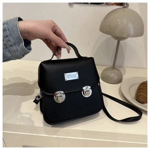Close-up of vintage black bucket bag with silver push locks on a white desk