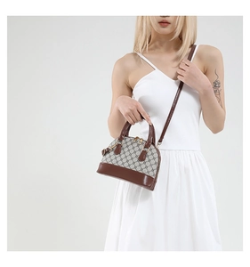 Macro shot of shell shoulder bag in monogram canvas with brown leather handles and detail