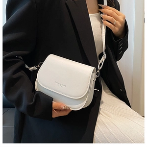 Detail of a white leather crossbody bag with FASHION TREND lettering and silver buckle