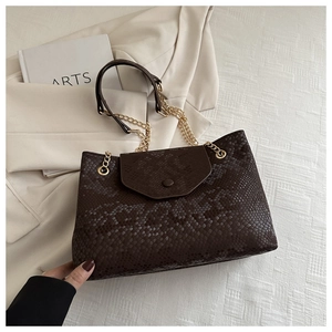 Détails d'un sac cabas marron foncé à motif serpent avec une élégante chaîne dorée
