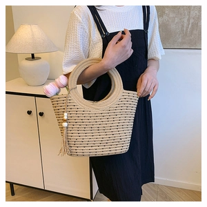 Detail of beige woven straw tote bag with round handles, tassels and tulip decorations