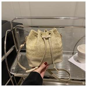 Detail of woven straw bucket bag with beige leather drawstring and shoulder strap