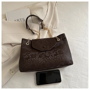 Détail du sac bandoulière marron foncé à relief serpent avec chaîne dorée et texture chic