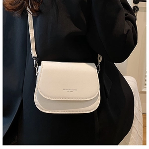 Detail of white leather crossbody bag with black text print and silver metal buckle