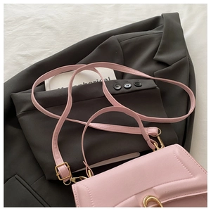 Detail of pink PU leather flap bag with gold horseshoe buckle and textured finish