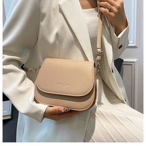 Close-up of beige crossbody bag with silver buckle and Fashion Trend logo on flap