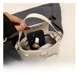Détail de l'intérieur du sac à bandoulière beige contenant un téléphone et du rouge