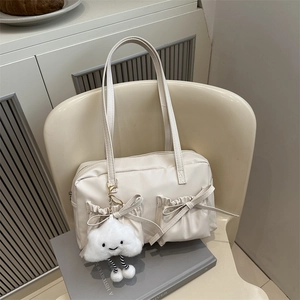 Elegant off-white nylon tote bag with bow pockets and a cute cloud charm on a chair