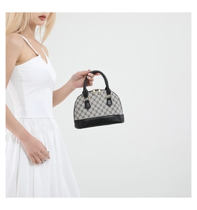 Detailed side view of a vintage mini shell handbag with grey monogram canvas and black leather