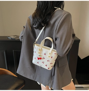 Detail of white tote bag with cherry print, adjustable strap and 3D cherry charm