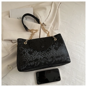 Détail de la texture serpent noire du sac à main avec chaîne dorée et référence de téléphone