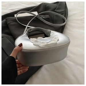 Silver satin heart bag with lace trim held against a black blazer for a stylish look