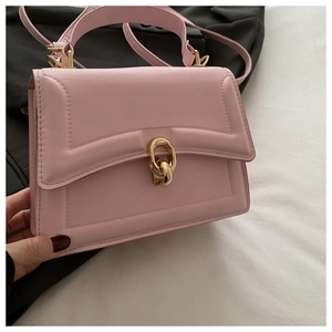 Detail of pink faux leather crossbody bag with elegant gold metal knot twist lock closure