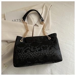 Détail d'un sac à main noir à motif serpent avec une élégante chaîne en métal doré