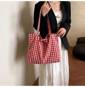 Detail of red and white gingham tote bag with bow decoration on model shoulder