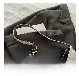 Detail of white crocodile pattern leather handbag with silver chain and comfortable handle