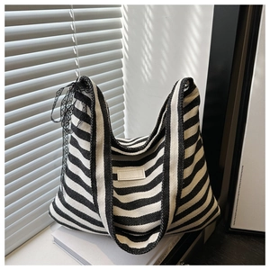 Close-up of black and white striped canvas tote bag with a decorative lace bow detail