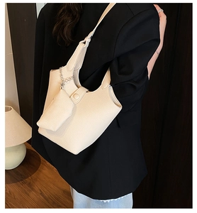 Detail of cream leather bucket bag with pebble texture and metallic chain accessory