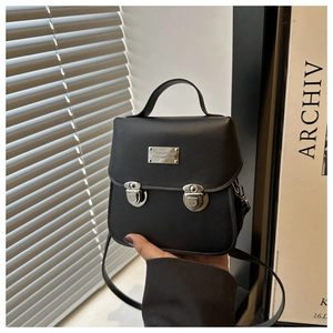 Macro view of black crossbody bag with silver buckle closures and matte leather texture