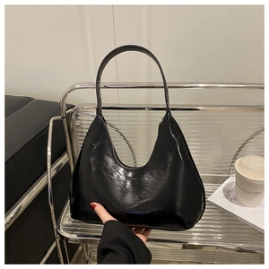 Detail of black glossy crescent shoulder bag with minimalist embossed logo on leather