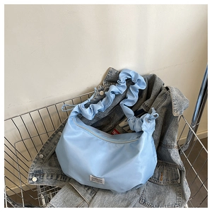 Détail du sac croissant plissé bleu clair avec étiquette mode et bandoulière froncée