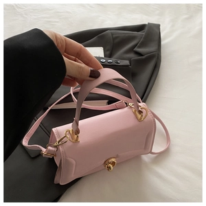 Detailed view of a pink minimalist crossbody bag with gold twist lock held by a model